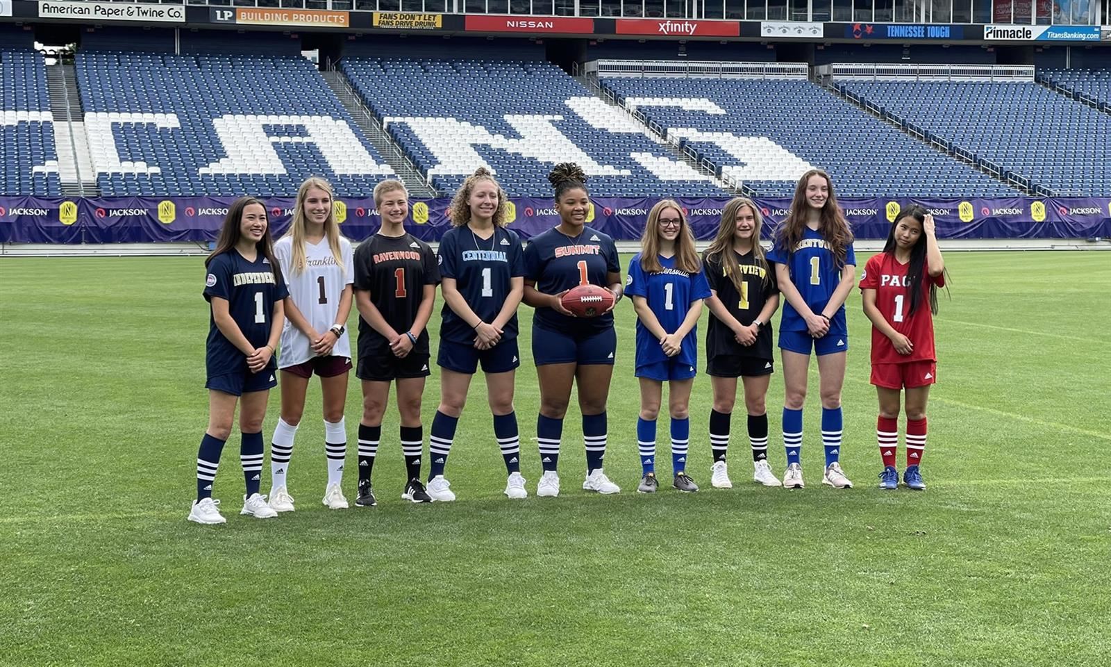 Girls in flag football uniforms stand in a line
